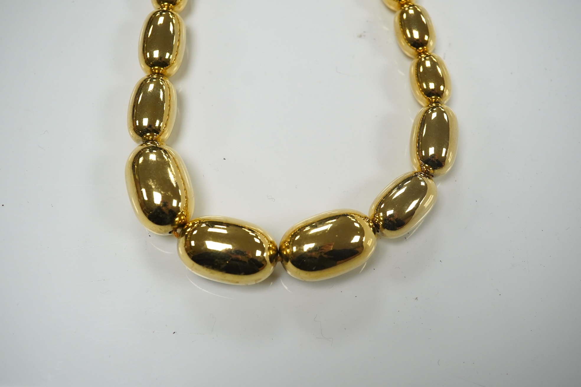 A modern gilt metal graduated oval bead costume necklace, 72cm. Condition - fair to good